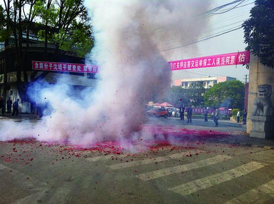 市民在普洱市主干道振興大道的金孔雀交通運(yùn)輸集團(tuán)有限公司門前燃放鞭炮，公司門前掛著“貪腐份子沈培平被查處，罪有應(yīng)得，大快人心?！钡臈l幅