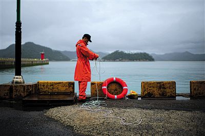 7月6日，韓國珍島，一名海岸警察在港口系救生圈。4月，客輪在珍島近海發(fā)生沉船事故后，仍有11人下落不明。