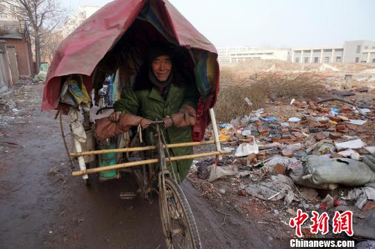 圖為老人走出窩棚，推著三輪車準(zhǔn)備出去撿拾廢品。周小云 攝