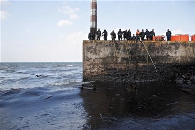 昨日，山東青島，清污人員正在海邊清理油污。