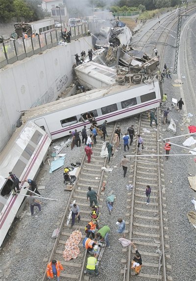 24日，救援人員在西班牙列車脫軌現(xiàn)場。一節(jié)車廂被強大的慣性拋上鐵道邊的高臺。