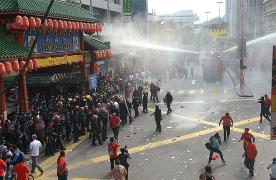 圖為鎮(zhèn)暴警察在吉隆坡的華人聚居地茨廠街向紅衣人噴射水柱