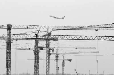 空中是起飛的飛機(jī)，下面是T2航站樓工地上林立的塔吊