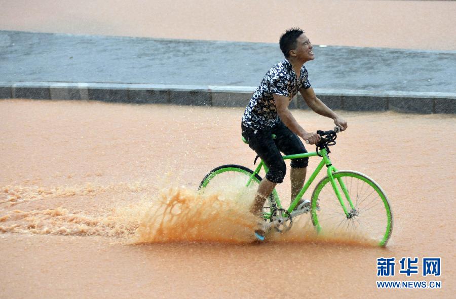 5月11日，一名行人在深圳街頭冒雨騎行。