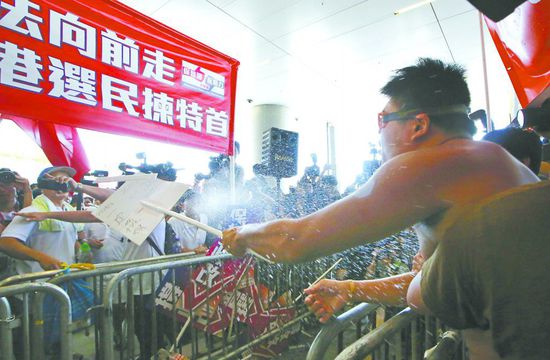 17日，在香港立法會(huì)外，一名反對(duì)政改的男子向支持派人群投擲標(biāo)牌。