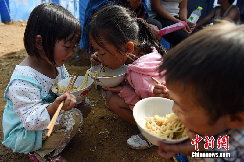 2014年8月6日，云南魯?shù)辇堫^山災(zāi)區(qū)，兒童在帳篷外吃飯。